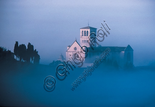 Veduta della Basilica di San Francesco ad Assisi avvolta dalla nebbia al mattino, architettura gotica umbra