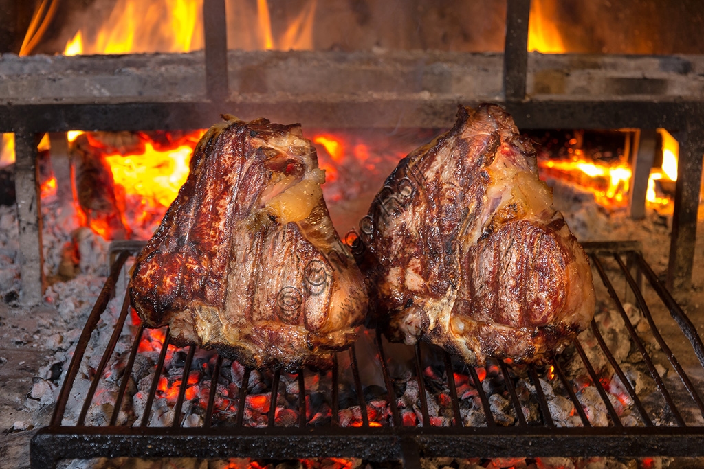 Bistecca alla Fiorentina, tipica carne alla brace toscana, servita al sangue su tagliere di legno.