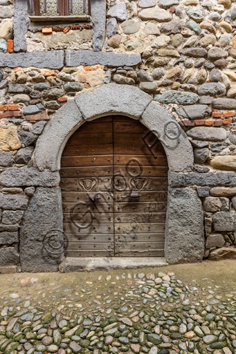 Architectural detail of the historic front door on a street within the medieval Ricetto of Candelo, Italy