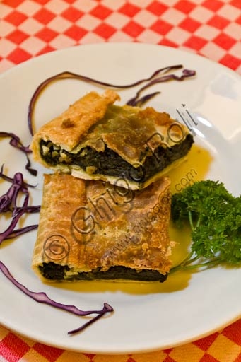 Erbazzone Reggiano, torta salata tipica dell'Emilia Romagna, servita a fette su tagliere di legno.