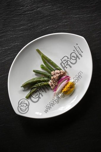 Foto di un'insalata di fagiolini e tonno con cipolla e uovo sodo in una ciotola bianca