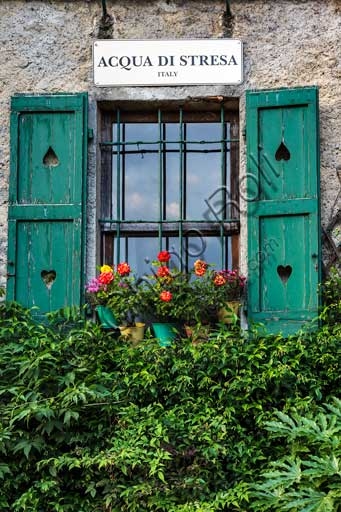 View of Isola Pescatori village with window, flowers and traditional sign on Lake Maggiore