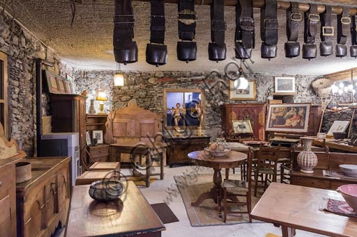 Interno del negozio di antiquariato a Bormio con mobili antichi valtellinesi in legno massello.