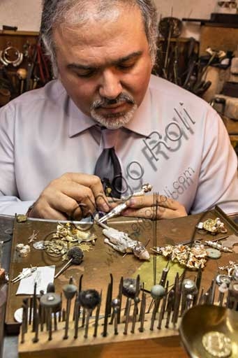 Paolo Penko crafting a small gold Pinocchio sculpture at his goldsmith workshop bench in Florence, Italy