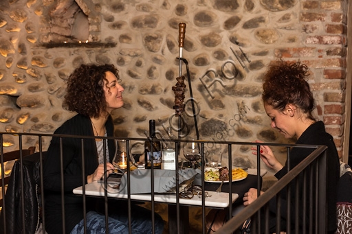 Two young customers having dinner at Restaurant Il Torchio 1763 inside the Ricetto of Candelo, Piedmont