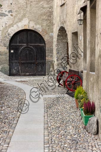 Fotografia della tipica via lastricata nel centro storico di Bormio, con edifici in pietra e facciate affrescate