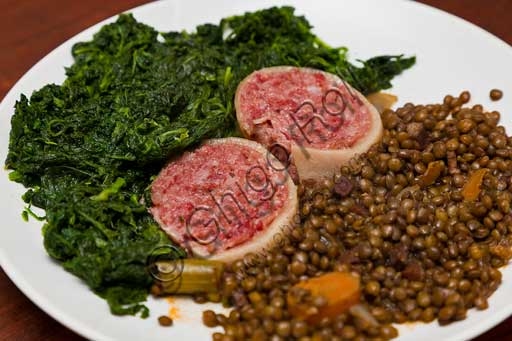 Cooked Modena Zampone served on a plate with a side of lentils and spinach