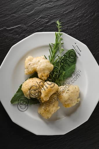 Dish of crispy fried salt cod garnished with fresh sage leaves and rosemary sprigs