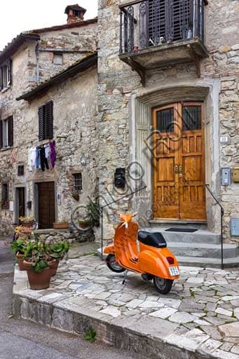 Photograph of a partial view of Radda in Chianti with a Vespa scooter parked on a cobbled street