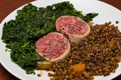 Cooked Modena Zampone served on a plate with a side of lentils and spinach