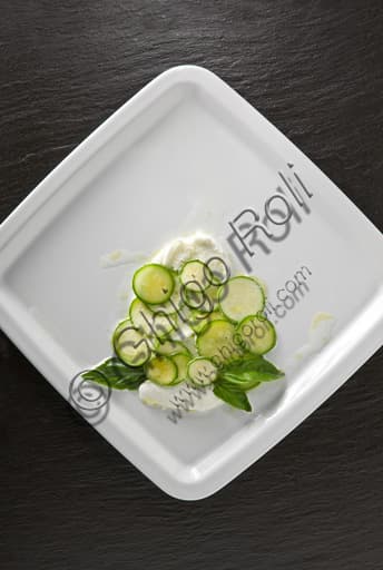 Piatto estivo fresco con mozzarella, fette di zucchina e foglie di basilico fresco