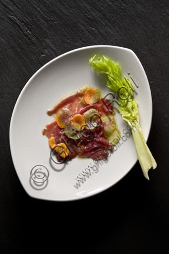 Plate of thinly sliced raw beef carpaccio with fresh carrot and celery garnish