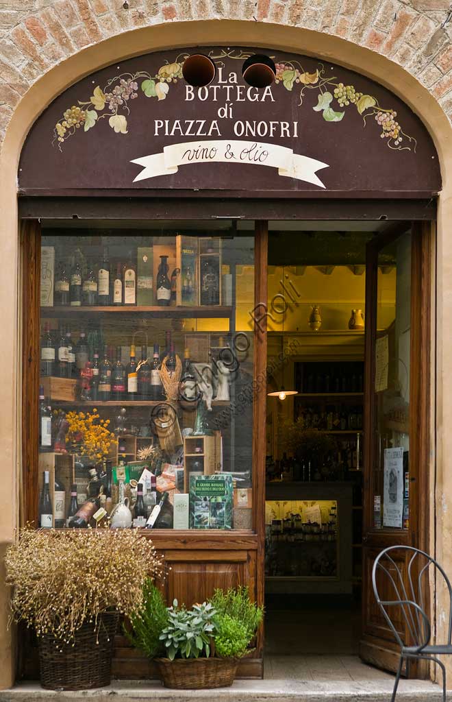 Interno della Bottega di Piazza Onofri a Bevagna con esposizione di bottiglie di vino e tavoli per degustazione