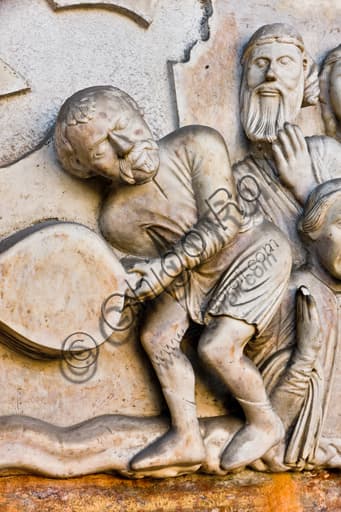 Dettaglio scultoreo del carnefice con mantice, lunetta del Martirio di San Lorenzo, portale Duomo di Genova (1225 c.)