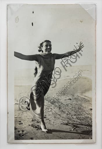 Fotografia in bianco e nero di Marcello Dudovich: donna che corre sulla spiaggia di Santa Gallura con le braccia aperte, stampa in gelatina al bromuro d'argento