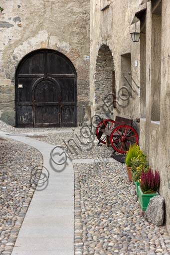 Fotografia della tipica via lastricata nel centro storico di Bormio, con edifici in pietra e facciate affrescate