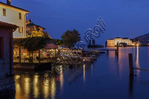 Veduta notturna del lungolago e pontile di Isola Pescatori sul Lago Maggiore, con Isola Bella e il Palazzo Borromeo illuminati in background.