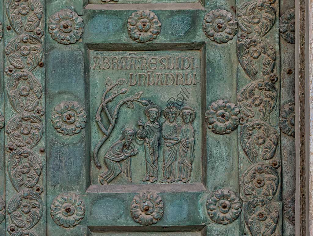 Duomo di Monreale, Porta di Bonanno Pisano (1185-6): formella bronzea con "Abramo e i tre angeli" (scena dall'Antico Testamento).La porta è firmata: "Bonanno civis pisanus". Iconograficamente nei cinque ordini inferiori vi sono scene del Vecchio Testamento, sette dedicate alla storia di Adamo ed Eva, e altre sei ad altrettante coppie di profeti mentre nei cinque superiori scene del Nuovo, al sommo Cristo e Maria nella gloria del Paradiso.