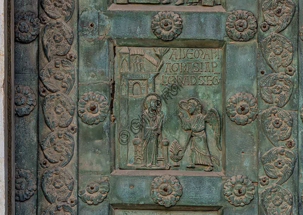 Duomo di Monreale, Porta di Bonanno Pisano (1185-6): formella bronzea con "Annunciazione" (scena dal Nuovo Testamento).La porta è firmata: "Bonanno civis pisanus". Iconograficamente nei cinque ordini inferiori vi sono scene del Vecchio Testamento, sette dedicate alla storia di Adamo ed Eva, e altre sei ad altrettante coppie di profeti mentre nei cinque superiori scene del Nuovo, al sommo Cristo e Maria nella gloria del Paradiso.