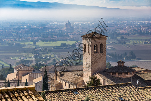 Assisi: veduta di tetti e del campanile dell'Abbazia di San Pietro. Sullo sfondo, nella nebbia, si intravvede la cupola del Santuario della Porziuncola.