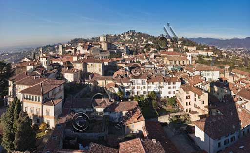 Bergamo, Città alta: veduta della città verso Ovest dalla Torre Civica, detta il Campanone. A sinistra, il Palazzo Vescovile con i suoi Giardini. Al centro, la Chiesa e il Seminario di Papa Giovanni XXIII. Sullo sfondo, il Colle e il Castello di San Vigilio (IX secolo). A destra, si intravvede la Val Brembana.