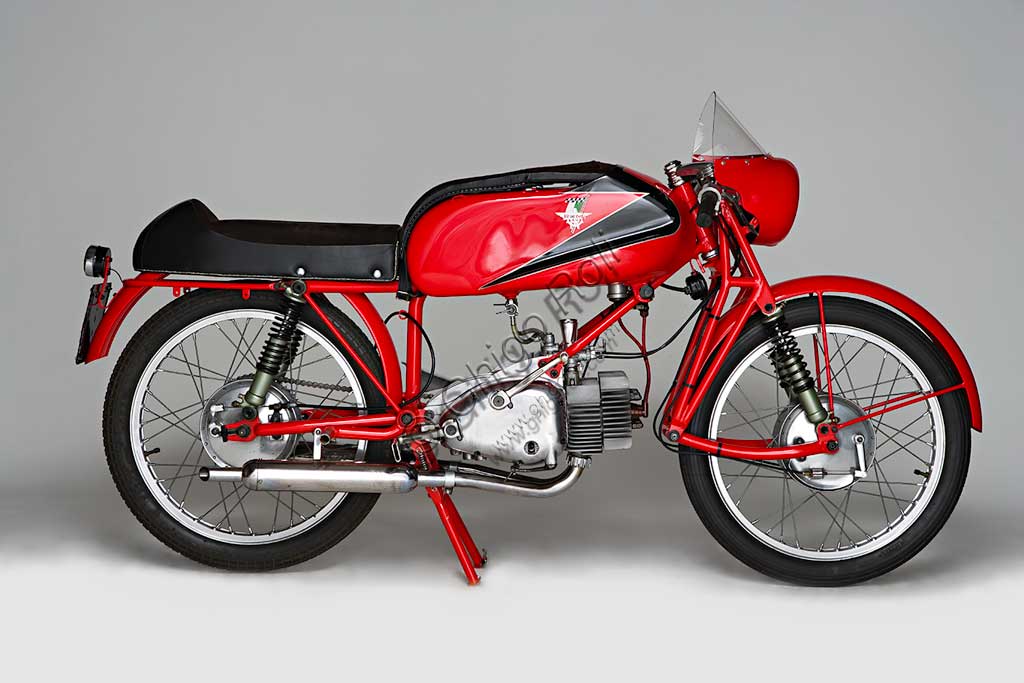 Moto d'epoca Rumi Junior 125.Marca: Fonderie Officine Rumimodello: Junior 125nazione: Italia - Bergamoanno: 1956condizioni: restauratacilindrata: 124,6 (alesaggio e corsa 42 x 45)motore: bicilindrico orizzontalecambio: in blocco a quattro rapportiDonnino Rumi subentra al padre nella fonderia per bronzo da questi creata. Durante la Seconda Guerra Mondiale rifiuta di convertire la produzione a scopi bellici e diventa partigiano latitante. Nel dopoguerra, alla domanda di mezzi di trasporto economici, risponde affiancando la produzione di motoleggere a quella già avviata di macchine tessili e per pastifici. Con l'aiuto dell'amico progettista nautico Pietro Vassena, nel 1949 è in grado di presentare al salone di Milano la prima, innovativa, motocicletta Rumi.La Junior deriva dalla "Bicarburatore" monta una forcella Earles, ed è fin dall'inizio destinata alle corse. Viene venduta a corridori privati sia italiani che stranieri e, grazie alla sua agilità, riscuote grande successo.