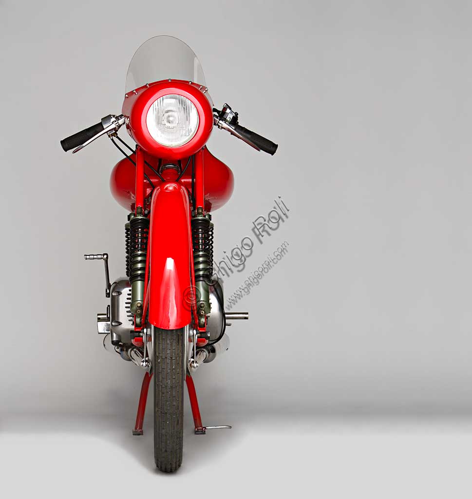 Moto d'epoca Rumi Junior 125.Marca: Fonderie Officine Rumimodello: Junior 125nazione: Italia - Bergamoanno: 1956condizioni: restauratacilindrata: 124,6 (alesaggio e corsa 42 x 45)motore: bicilindrico orizzontalecambio: in blocco a quattro rapportiDonnino Rumi subentra al padre nella fonderia per bronzo da questi creata. Durante la Seconda Guerra Mondiale rifiuta di convertire la produzione a scopi bellici e diventa partigiano latitante. Nel dopoguerra, alla domanda di mezzi di trasporto economici, risponde affiancando la produzione di motoleggere a quella già avviata di macchine tessili e per pastifici. Con l'aiuto dell'amico progettista nautico Pietro Vassena, nel 1949 è in grado di presentare al salone di Milano la prima, innovativa, motocicletta Rumi.La Junior deriva dalla "Bicarburatore" monta una forcella Earles, ed è fin dall'inizio destinata alle corse. Viene venduta a corridori privati sia italiani che stranieri e, grazie alla sua agilità, riscuote grande successo.