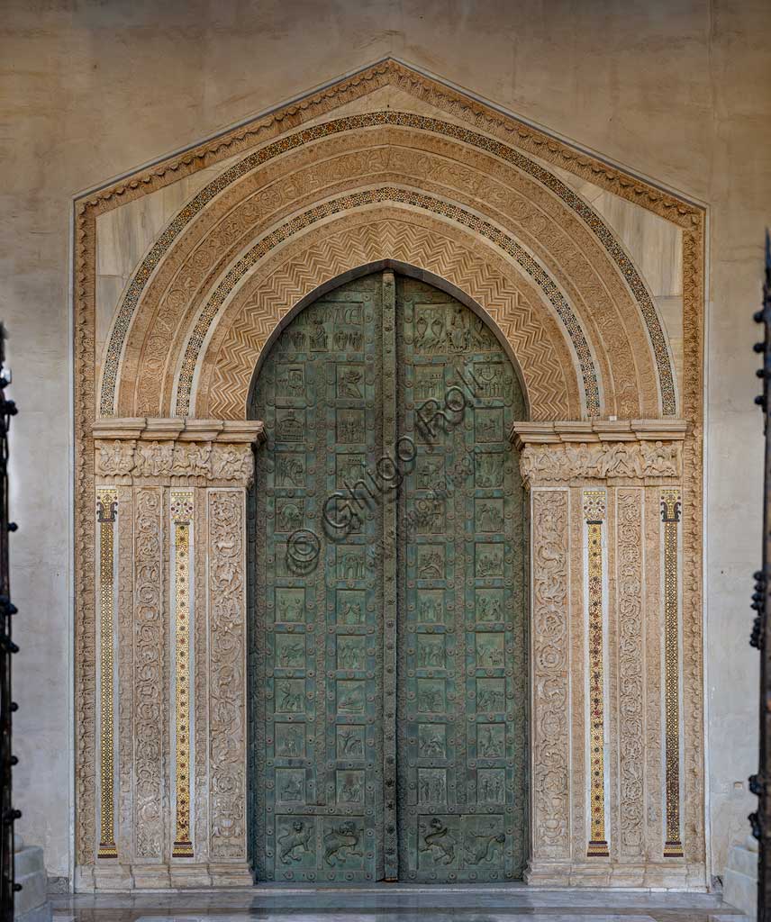 Duomo di Monreale: la Porta di Bonanno Pisano (1185-6).La porta è firmata: "Bonanno civis pisanus". Iconograficamente nei cinque ordini inferiori di fromelle bronzee vi sono scene del Vecchio Testamento, sette dedicate alla storia di Adamo ed Eva, e altre sei ad altrettante coppie di profeti mentre nelle formelle dei cinque superiori scene del Nuovo, al sommo Cristo e Maria nella gloria del Paradiso.