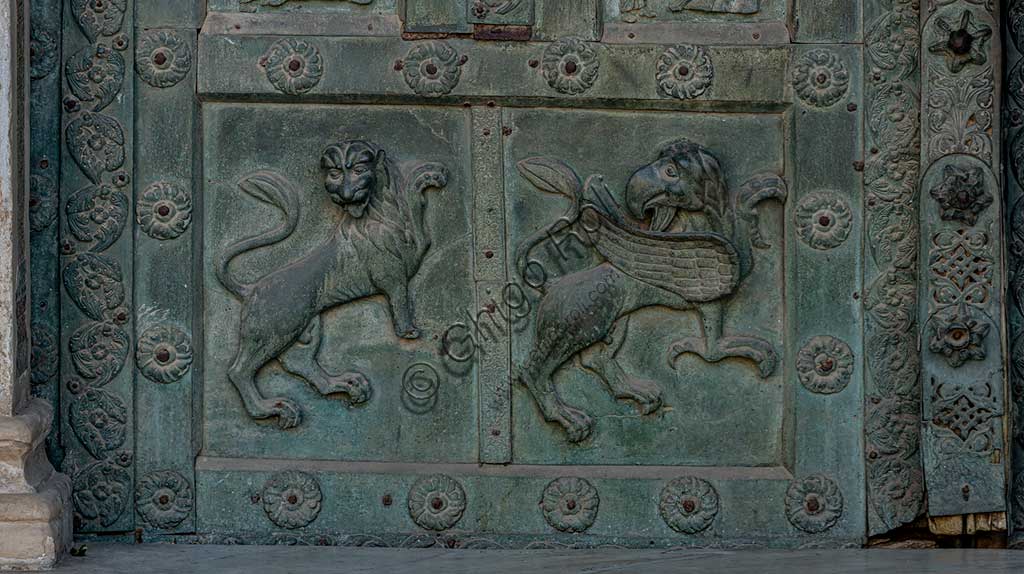 Duomo di Monreale, Porta di Bonanno Pisano (1185-6): formella bronzea con grifone e leone.La porta è firmata: "Bonanno civis pisanus". Iconograficamente nei cinque ordini inferiori vi sono scene del Vecchio Testamento, sette dedicate alla storia di Adamo ed Eva, e altre sei ad altrettante coppie di profeti mentre nei cinque superiori scene del Nuovo, al sommo Cristo e Maria nella gloria del Paradiso.