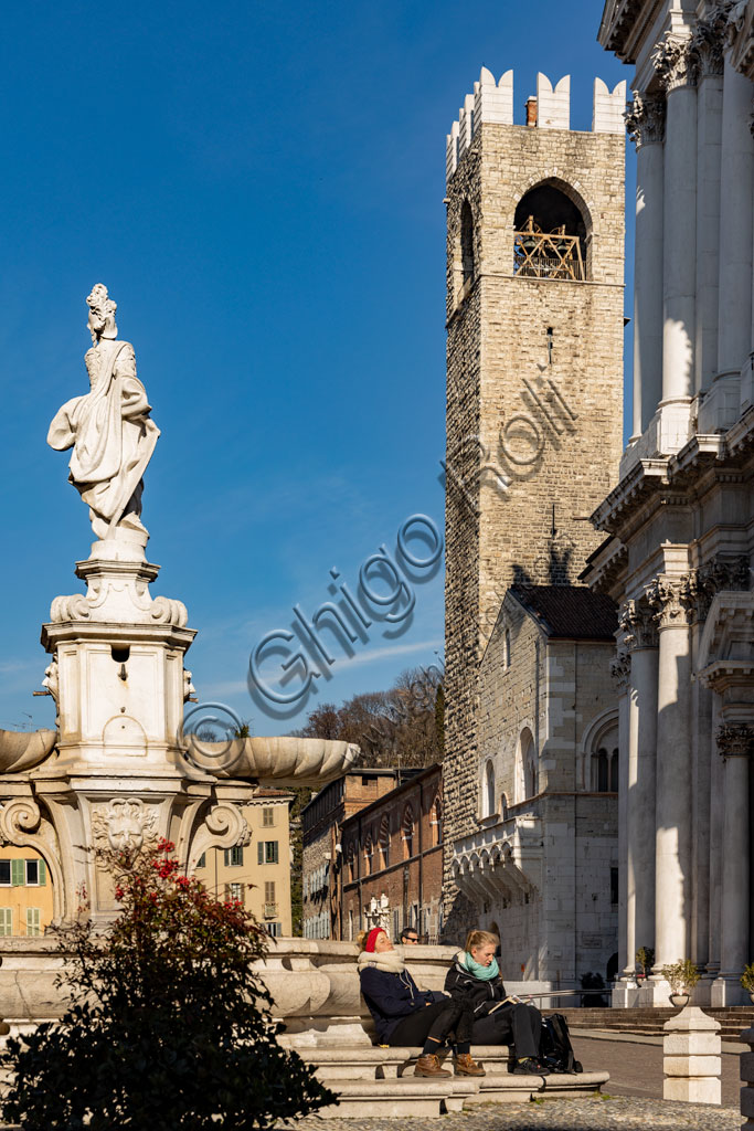 Brescia, Paolo VI Square: view. From the left, the Broletto with the Pégol Tower and the Loggia delle Grida; and part of the facade of the Duomo Nuovo  (the New Cathedral) , in late Baroque style with the facade of Botticino marble. In the foreground, the fountain with a copy of the neoclassical statue of Minerva, known as "Armed Brescia".
