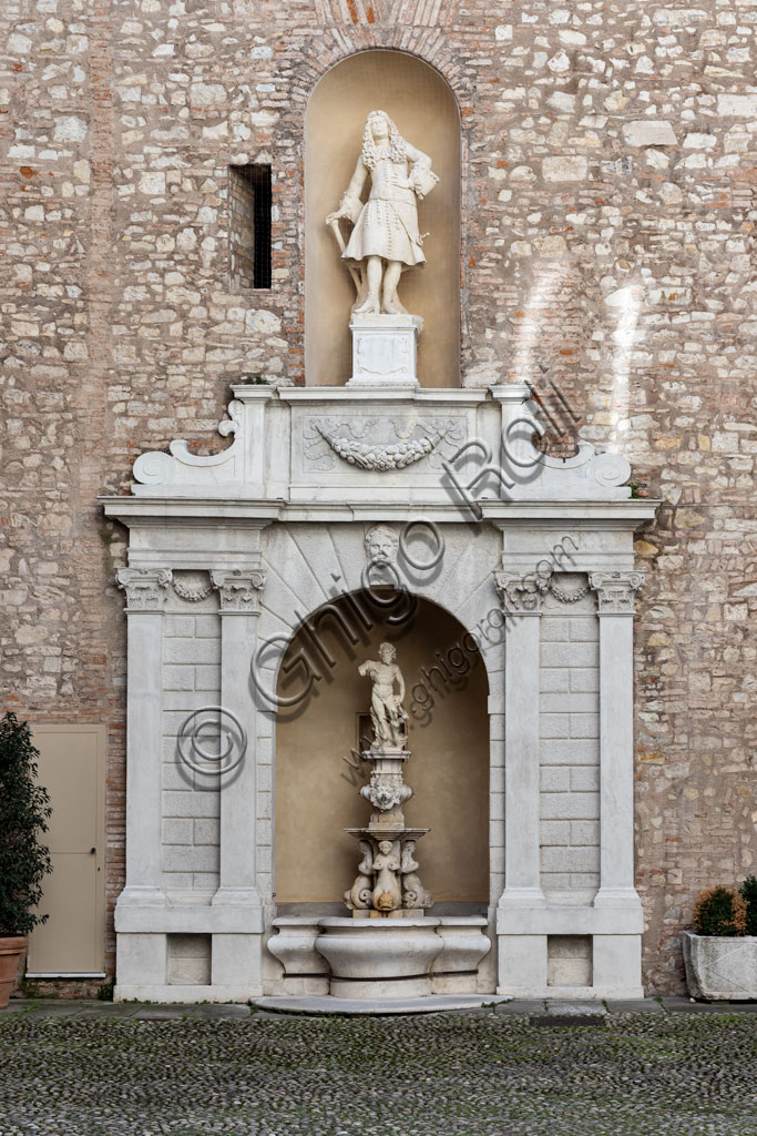 Brescia, Palazzo Martinengo Cesaresco Novarino: a 16th-century fountain with a niche for the pool and a statue of Neptune, surrounded by double Corinthian pilasters. At the top there is an eighteenth-century statue depicting Cesare Martinengo, or perhaps his daughter Scilla, who inherited this part of the building after his father's death.