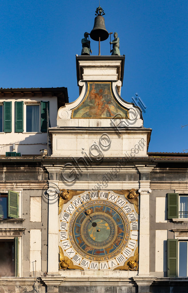 Brescia, piazza della Loggia (a Renaissance square where the Venetian influence is evident): the Clock Tower (1540 - 1550) with the astronomical quadrant with concentric rings, decorated in gold and blue and with symbols of the Zodiacal signs. Above the dial, a plinth adorned with the symbol of the sun and a volute base that stand as a pedestal for the automata, the popular Macc de le ure (crazy hours) that hammer at every hour on the bell.