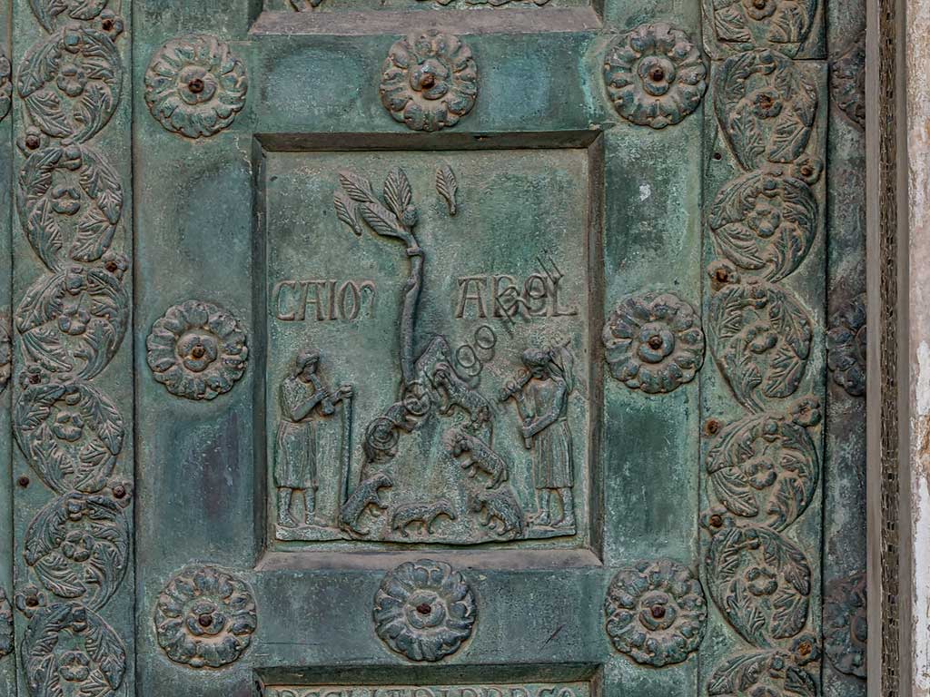 Duomo di Monreale, Porta di Bonanno Pisano (1185-6): formella bronzea con "Caino e Abele" (scena dall'Antico Testamento).La porta è firmata: "Bonanno civis pisanus". Iconograficamente nei cinque ordini inferiori vi sono scene del Vecchio Testamento, sette dedicate alla storia di Adamo ed Eva, e altre sei ad altrettante coppie di profeti mentre nei cinque superiori scene del Nuovo, al sommo Cristo e Maria nella gloria del Paradiso.