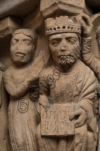 Modena, Ghirlandina Tower, Torresani Hall: the "Capital of the Judge" or "of the Upright Judge and of the Corrupt Judge", work by Campionesi masters, XII - XIII century.There are three carved scenes. Detail of two scenes: the good judge crowned and a barefoot man with his hand clasped in the act of supplication. The inscription informs us that a crooked judge corrupted by money will give a judgment not in accordance with his conviction.