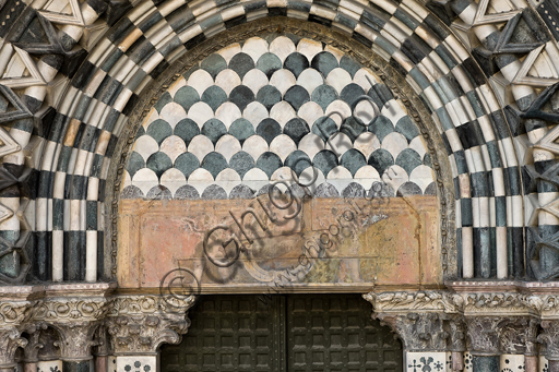 , Genoa, Duomo (St. Lawrence Cathedral), West side, the façade, the right doorway: the lunette and architrave with "Cartouche between shield-bearing angels" (early XVII century).