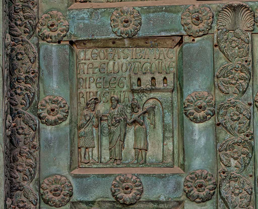 Duomo di Monreale, Porta di Bonanno Pisano (1185-6): formella bronzea con "Cena in Emmaus" (scena dal Nuovo Testamento).La porta è firmata: "Bonanno civis pisanus". Iconograficamente nei cinque ordini inferiori vi sono scene del Vecchio Testamento, sette dedicate alla storia di Adamo ed Eva, e altre sei ad altrettante coppie di profeti mentre nei cinque superiori scene del Nuovo, al sommo Cristo e Maria nella gloria del Paradiso.