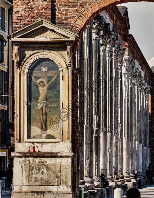  Church of S. Lorenzo Maggiore or alle Colonne: view of the 16 Roman Corinthian columns,  II-III century.  in the foreground “Crucifixion", a painting at the right end of the colonnade.