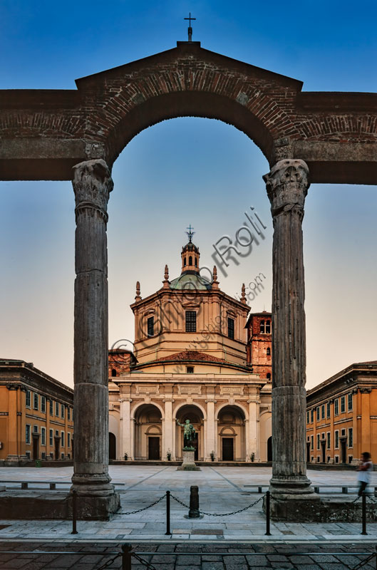 Chiesa di S. Lorenzo Maggiore o alle Colonne: veduta serale della facciata e del sagrato con al centro la statua bronzea di Costantino imperatore. In primo piano le colonne romane.