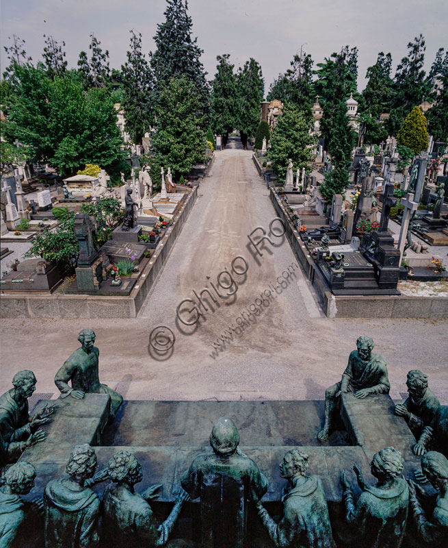  Monumental Cemetery: view of the cemetery. In the foreground, the Campari aedicule, with the bronze sculptural group "The Last Supper" by Giannino Castiglioni (1935) placed on a base obtained from a porphyritic erratic boulder. The funeral monument was erected (1936-1939) by the will of Davide Campari (1867-1936), owner of the homonymous company producing beverages and liqueurs, whose father Gaspare around 1865 had started the production of the drink "bitter" in Milan.