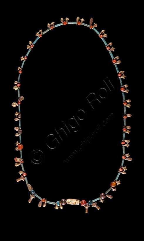 Museo Civico Archeologico di Bologna: collana con cartiglio del dio Aton, dettaglio del cartiglio.Inventario EG 3069.Nuovo Regno: XVIII dinastia, regno di Akhenaton (1353 - 1336 a.C.).Fra i vari elementi che compongono questa collana -perline alternate a tubetti, testine della dea Hathor ed elementi vegetali- spicca un piccolo cartiglio in lamina d’oro su cui è scritto a sbalzo uno dei nomi del dio Aton. Questa divinità, che rappresenta per gli Egiziani il disco del sole, assunse grande importanza durante il regno del faraone Amenhotep IV/Akhenaton (1353-1336 a.C.), soppiantando per un breve periodo il culto dell’importantissimo dio tebano Amon. 