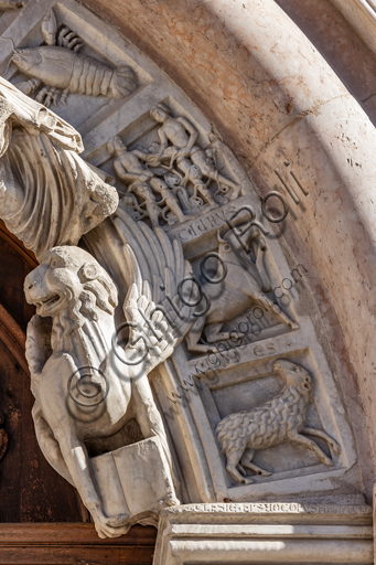  Foligno, Cathedral of  St. Feliciano, the façade:  the entrance door. Detail of the frieze of  the portal. The central portal, work of the masters Rodolfo and Binello, shows a solar disk in the lunette, in which there is the inscription with the date 1201, the year of completion of the facade; in the inner façade of the jambs there are then the reliefs with the Emperor Otto IV of Brunswick and Pope Innocent III, while the inner circle of the arch is decorated by the symbols of the evangelists and the Signs of the zodiac; in the outer circle a band of cosmatesque mosaics. The carved wooden portal was made in 1620.