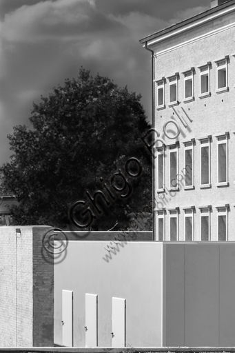  MEIS, National Museum of Italian Judaism and the Shoah in the town of Ferrara: detail of the façade and the surrounding wall flanked by a tree.The MEIS was realised in a building in via Piangipane which is part of the complex consisting of three blocks, enclosed by a double wall. The Museum is therefore the result of a work of conversion of the judicial prison in via Piangipane which was built between 1908 and 1912 based on a design by the engineers Bertotti and Facchini of the Civil Engineer Office. During the twenty years of fascism it became a place of detention for many anti-fascists. After the fall of the regime, on July 30,1943, 88 politic