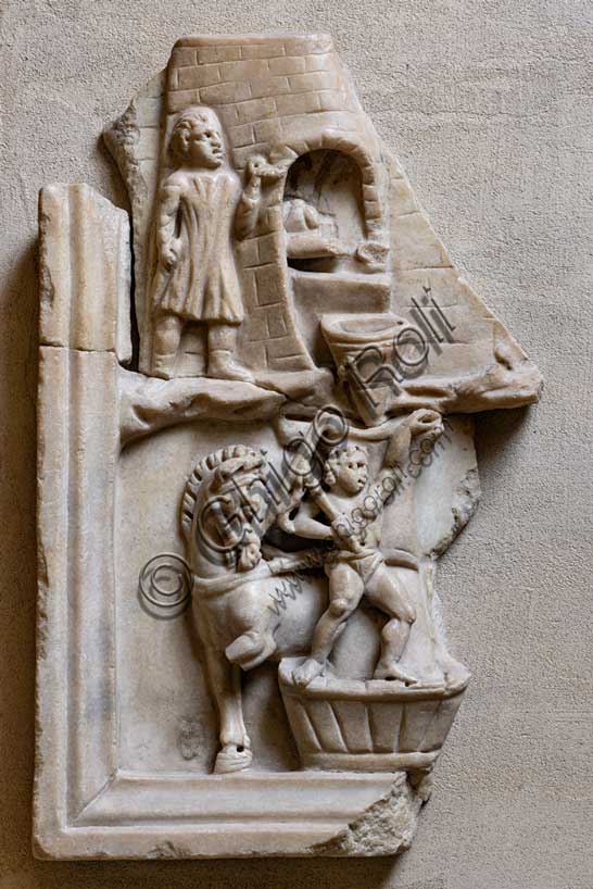 Museo Civico Archeologico di Bologna:rilievo con scena di pistrinum (panificio); rilievo frammentario, proveniente dalla collezione Marsili. Vi sono raffigurate le attività svolte in un panificio.Particolare della macinatura del grano con mola a trazione animale e cottura del pane. Inv ROM 1872