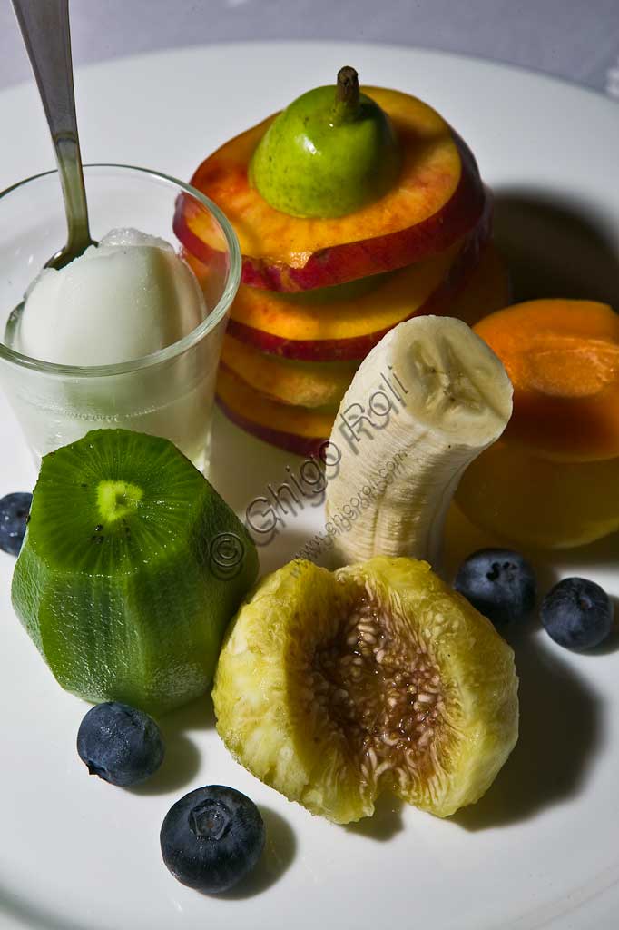  A dessert with fruit (kiwi, banana, peach, apricot, and fig) and icecream.