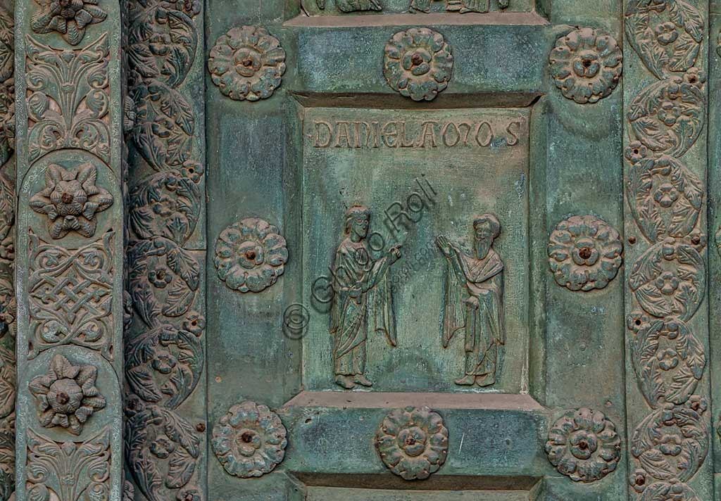 Duomo di Monreale, Porta di Bonanno Pisano (1185-6): formella bronzea con "Due profeti: Daniele e Amos." (scena dall'Antico Testamento).La porta è firmata: "Bonanno civis pisanus". Iconograficamente nei cinque ordini inferiori vi sono scene del Vecchio Testamento, sette dedicate alla storia di Adamo ed Eva, e altre sei ad altrettante coppie di profeti mentre nei cinque superiori scene del Nuovo, al sommo Cristo e Maria nella gloria del Paradiso.