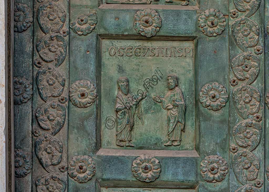 Duomo di Monreale, Porta di Bonanno Pisano (1185-6): formella bronzea con "Due profeti: Osea e Isaia." (scena dall'Antico Testamento).La porta è firmata: "Bonanno civis pisanus". Iconograficamente nei cinque ordini inferiori vi sono scene del Vecchio Testamento, sette dedicate alla storia di Adamo ed Eva, e altre sei ad altrettante coppie di profeti mentre nei cinque superiori scene del Nuovo, al sommo Cristo e Maria nella gloria del Paradiso.