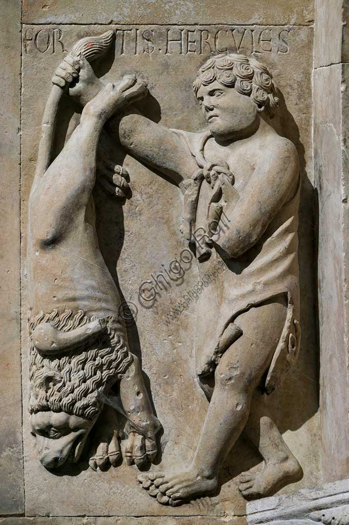 Fidenza, Duomo (St. Donnino Cathedral), Façade, the right portal, inside the protiro: "Hercules shows the Nemean lion he killed". Bas-relief by Benedetto Antelami and workshop.