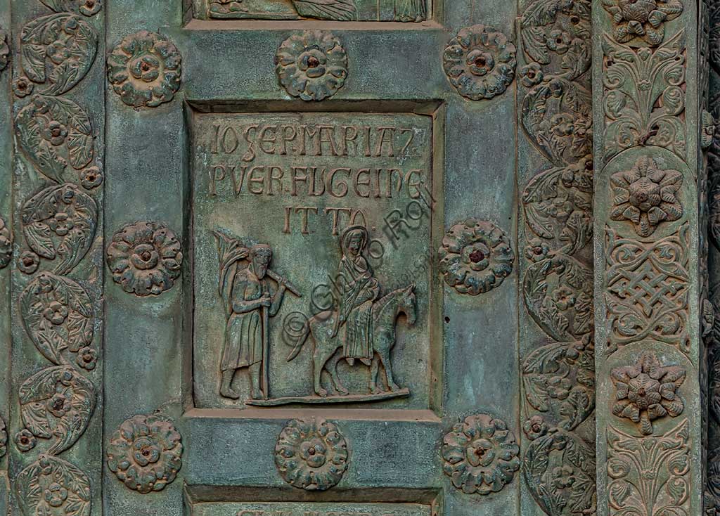 Duomo di Monreale, Porta di Bonanno Pisano (1185-6): formella bronzea con "Fuga in Egitto" (scena dal Nuovo Testamento).La porta è firmata: "Bonanno civis pisanus". Iconograficamente nei cinque ordini inferiori vi sono scene del Vecchio Testamento, sette dedicate alla storia di Adamo ed Eva, e altre sei ad altrettante coppie di profeti mentre nei cinque superiori scene del Nuovo, al sommo Cristo e Maria nella gloria del Paradiso.