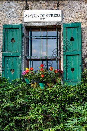 Isola Pescatori: scorcio del borgo con finestra, fiori e insegna.