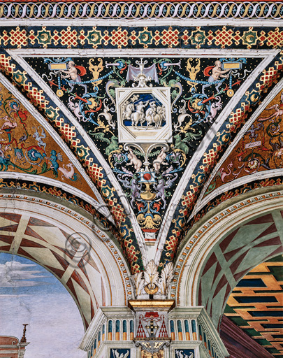 The Piccolomini Library, the vault: spandrel above the north-east wall between the third and the fourth story, frescoes attributed to Girolamo del Pacchia, Giacomo Pacchiarotto and Littifredi Corbizi. The decoration is inspired by the Domus Aurea and the motif of the ancient grotesques. The general scheme of the vault is probably due to Bernardino di Betto, known as Pinturicchio. At the centre grisaille with  a scene of an equestrian combat.